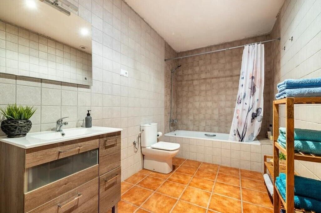 Une salle de bain comprenant des toilettes, un lavabo, une douche et un porte-serviettes.