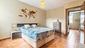Un dormitorio con cama, mesita de noche, cómoda y un mapa del mundo en la pared.