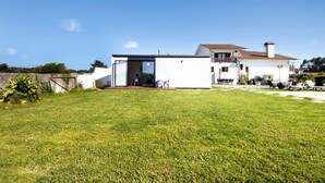Une maison moderne avec un toit plat, un balcon et une pelouse bien entretenue.