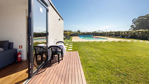 Une maison moderne dotée d’une terrasse, d’une piscine et d’un jardin arrière gazonné.