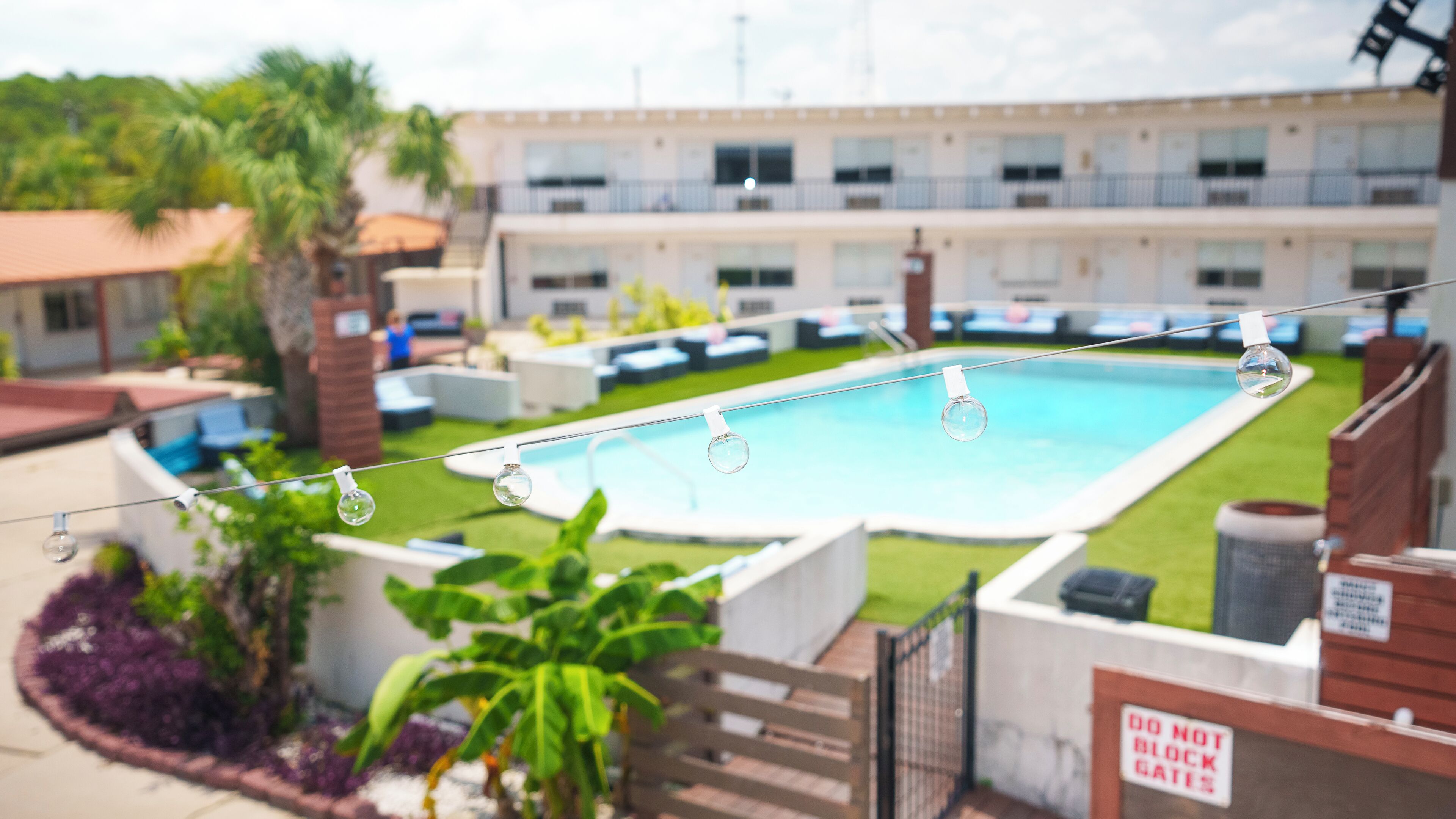 Une piscine offrant une vue dégagée sur les environs, notamment sur un bâtiment doté de nombreuses fenêtres et sur un jardin clos.