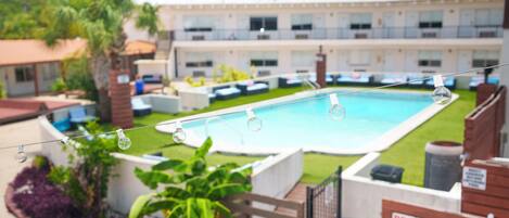 Une piscine offrant une vue dégagée sur les environs, notamment sur un bâtiment doté de nombreuses fenêtres et sur un jardin clos.