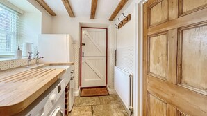 A laundry area with a washing machine, a sink, and a wooden door. - 3 bedroom accommodation in Sutton Benger, near Lacock (Sutton Benger, near Lacock)