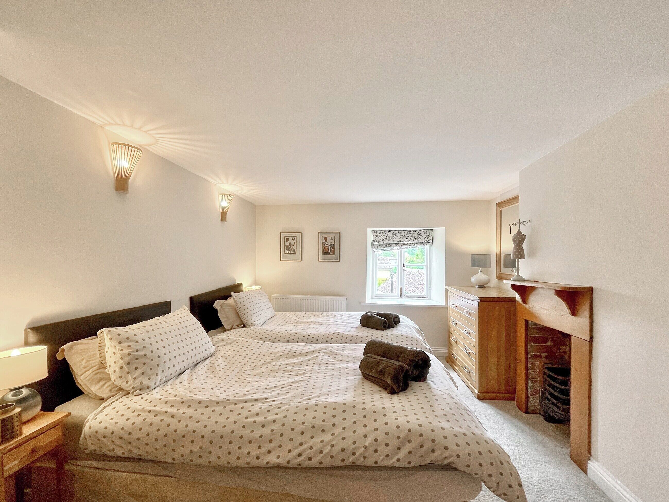 A bedroom with two beds, a dresser, a radiator, and a window with a view.