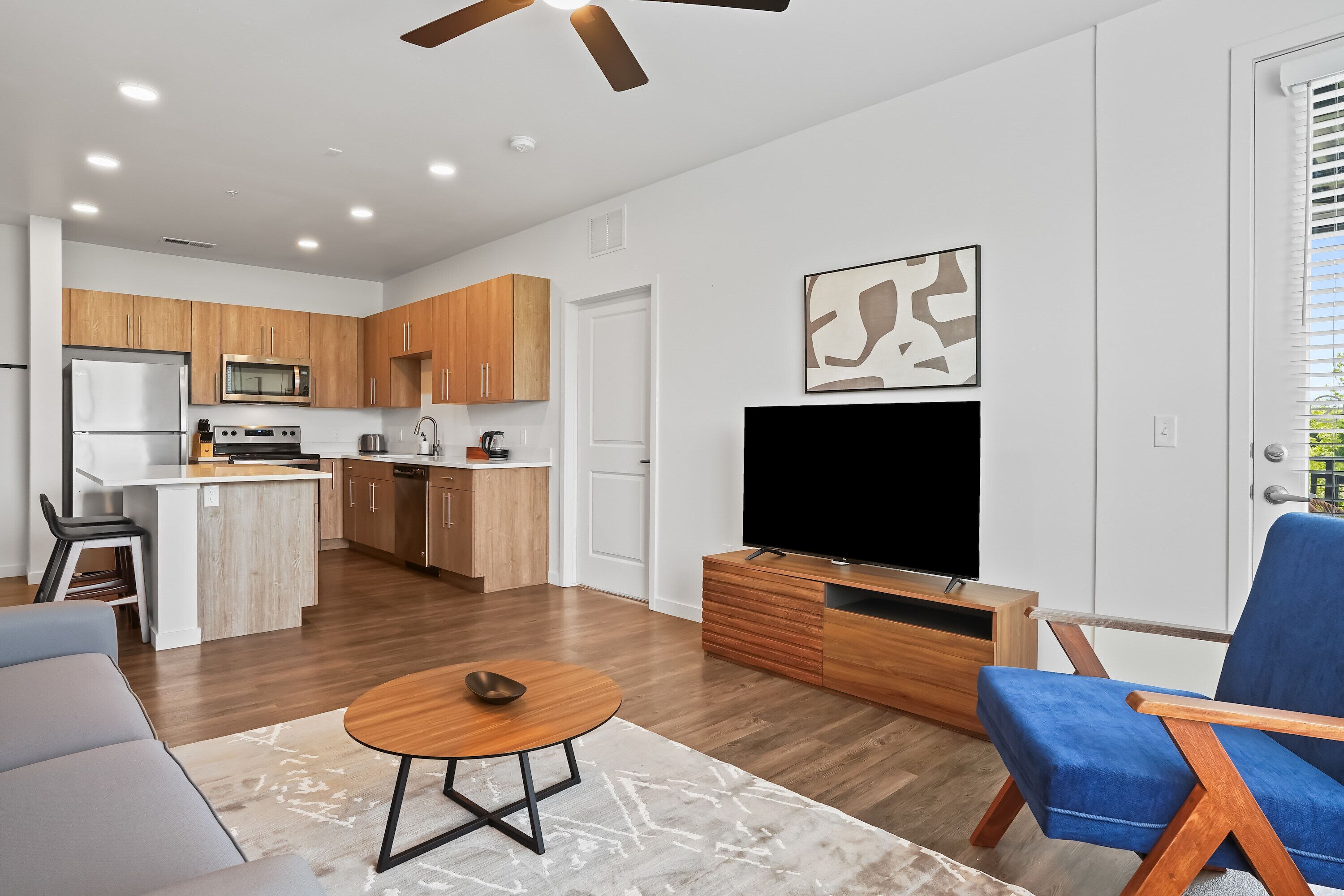 A modern kitchen with wooden cabinets, a built-in microwave, and a central island.