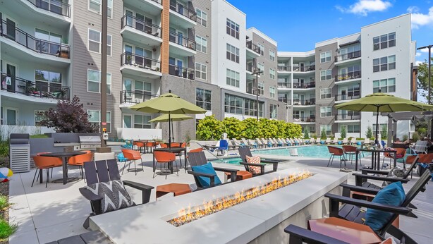 A modern outdoor pool area with lounge chairs and umbrellas, surrounded by multi-story residential buildings. - Kasa on the River Boise (Boise)