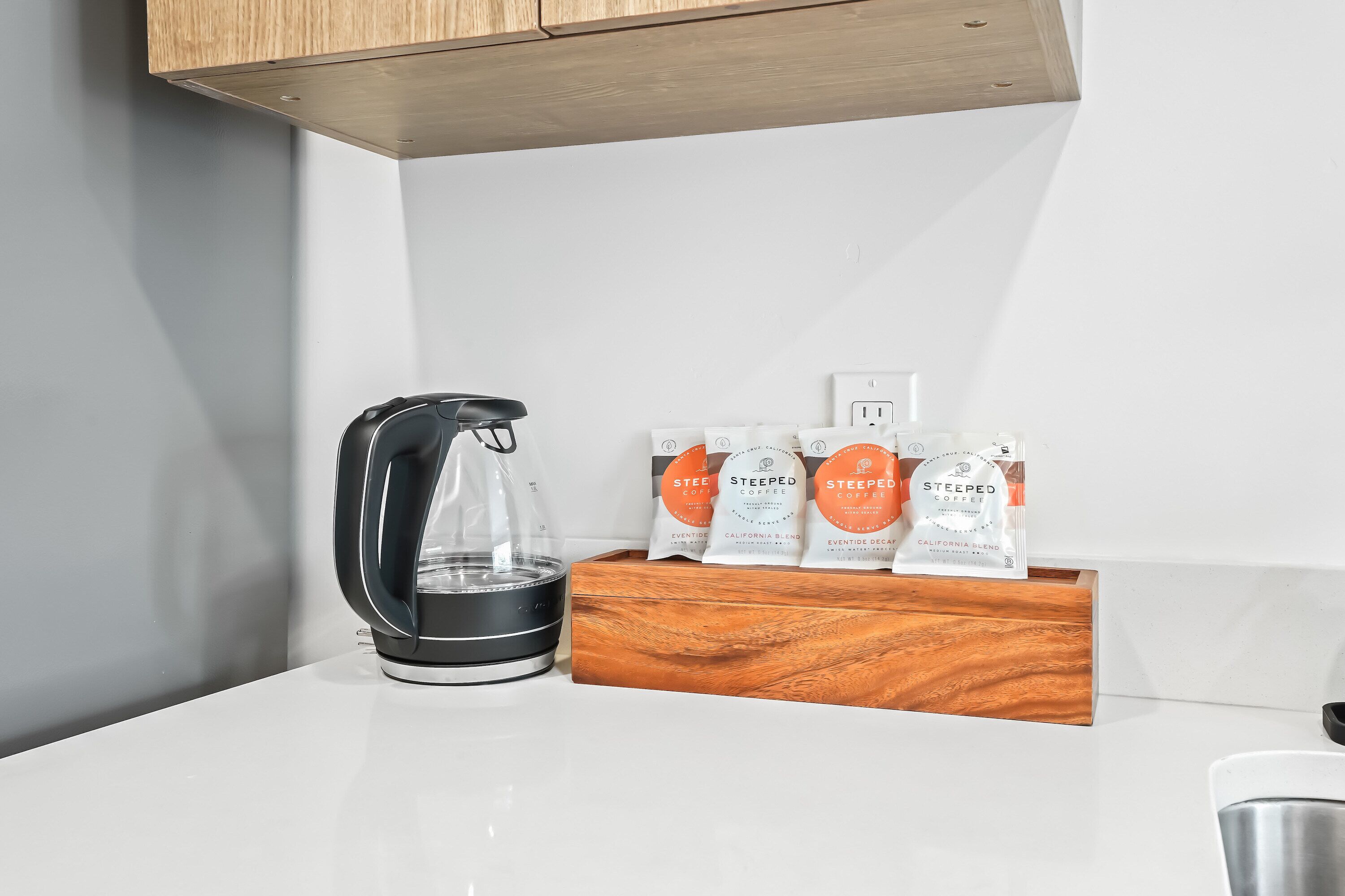 Una encimera de cocina con una cafetera y una caja de madera con cápsulas de café.