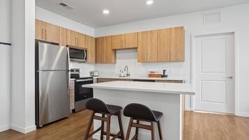Una cucina moderna con mobili in legno, elettrodomestici in acciaio inossidabile e un piano di lavoro bianco.