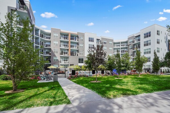 A modern apartment building with multiple balconies, a central courtyard with a bike rack, and a well-maintained lawn. - Kasa on the River Boise (Boise)