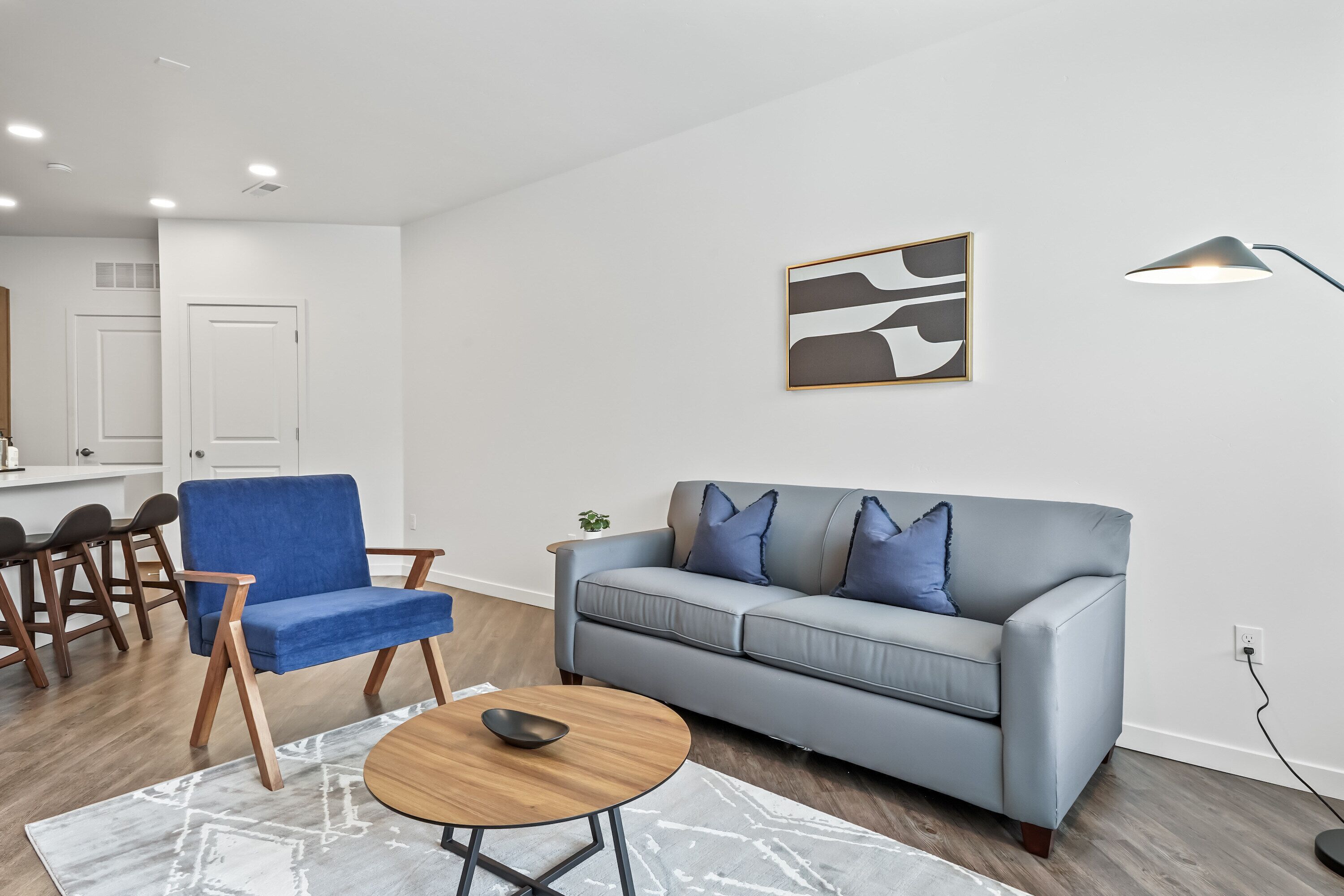 A modern living room with a blue sofa, a round coffee table, and a gray rug.