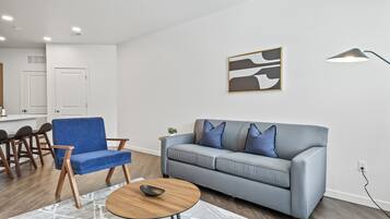 A modern living room with a blue sofa, a round coffee table, and a gray rug.