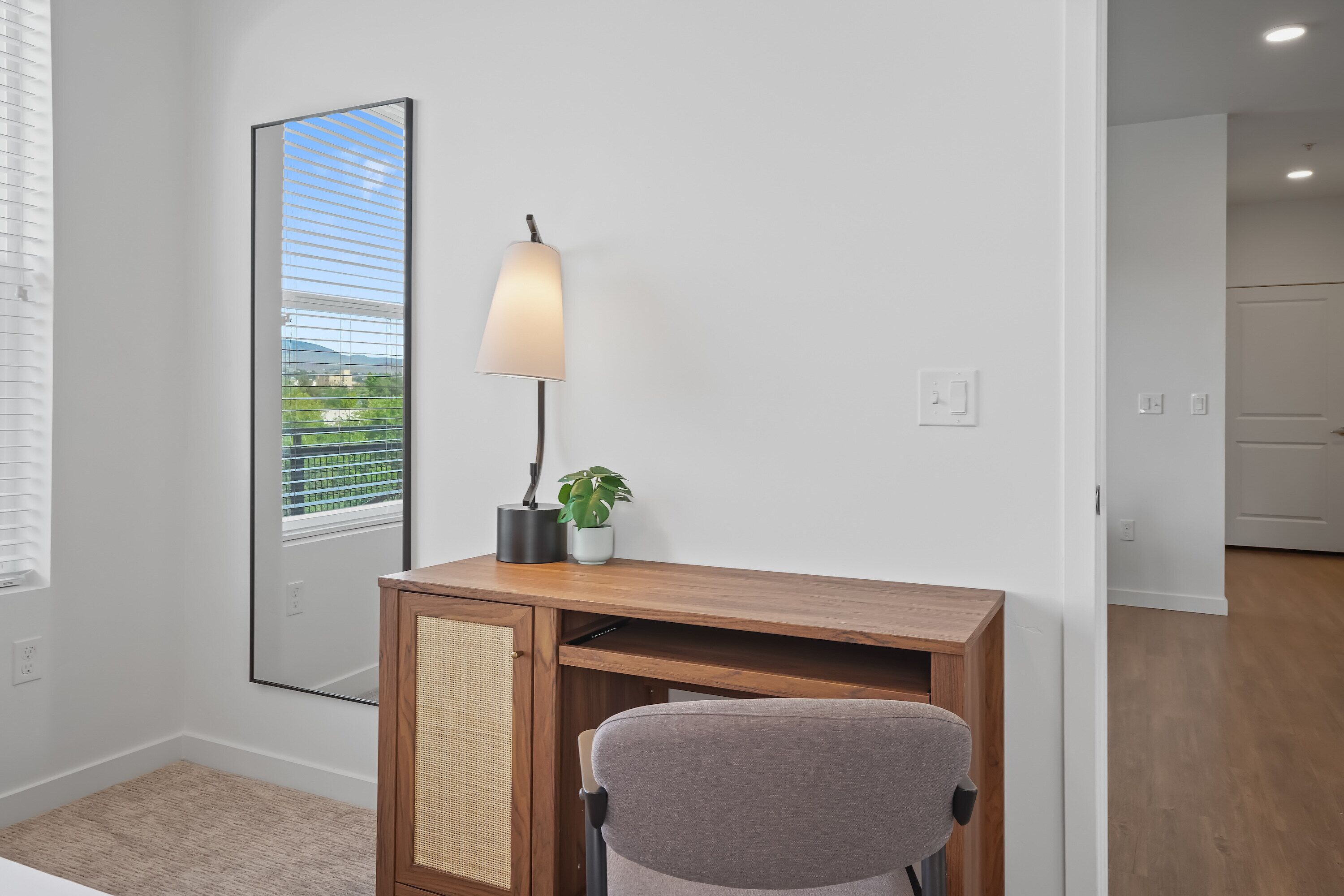 Un espace de bureau moderne comprenant un bureau, une chaise, une lampe et une plante en pot.