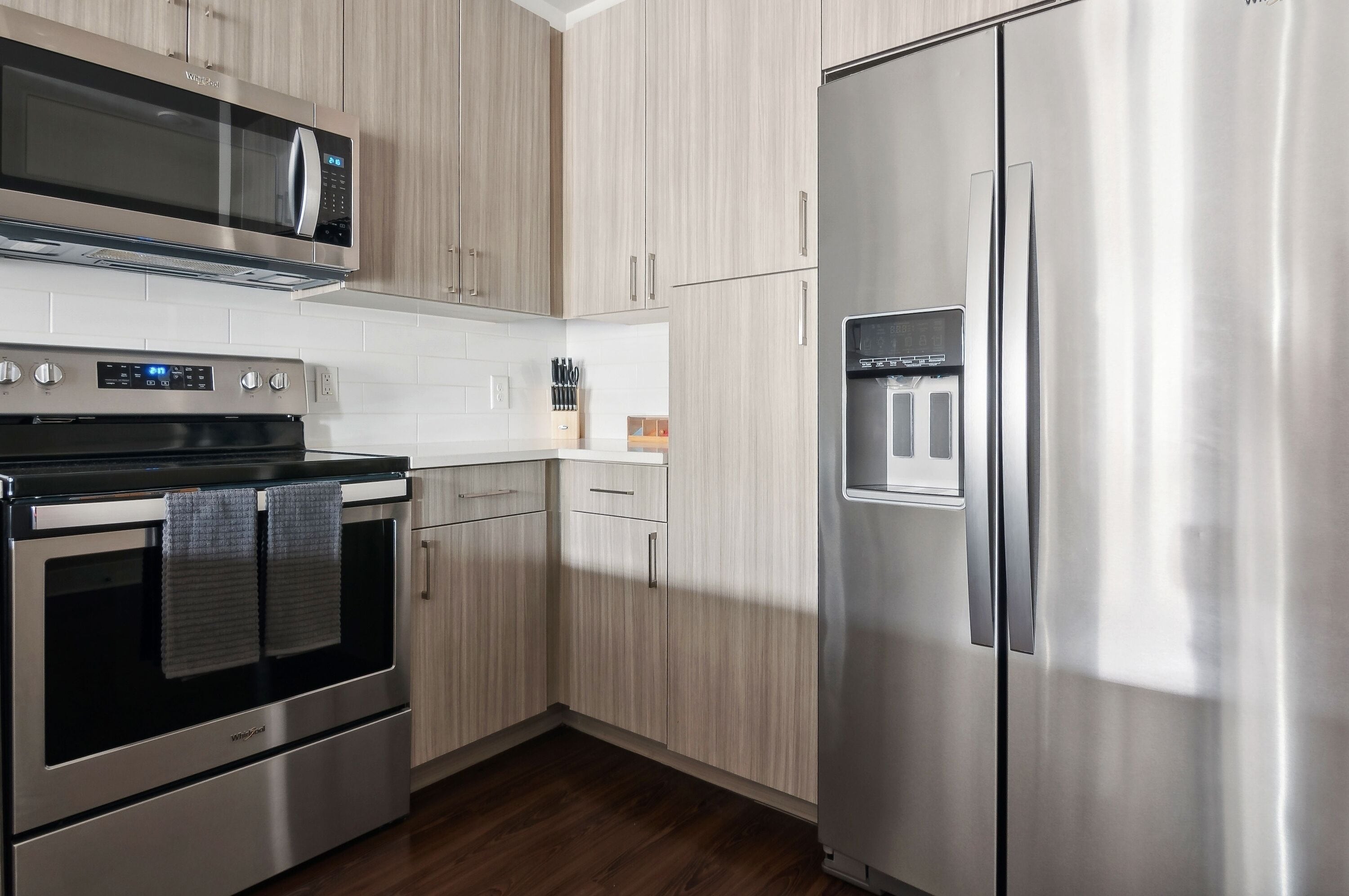 A modern kitchen with stainless steel appliances, wooden cabinets, and a built-in water dispenser.