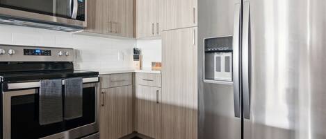 A modern kitchen with stainless steel appliances, wooden cabinets, and a built-in water dispenser.