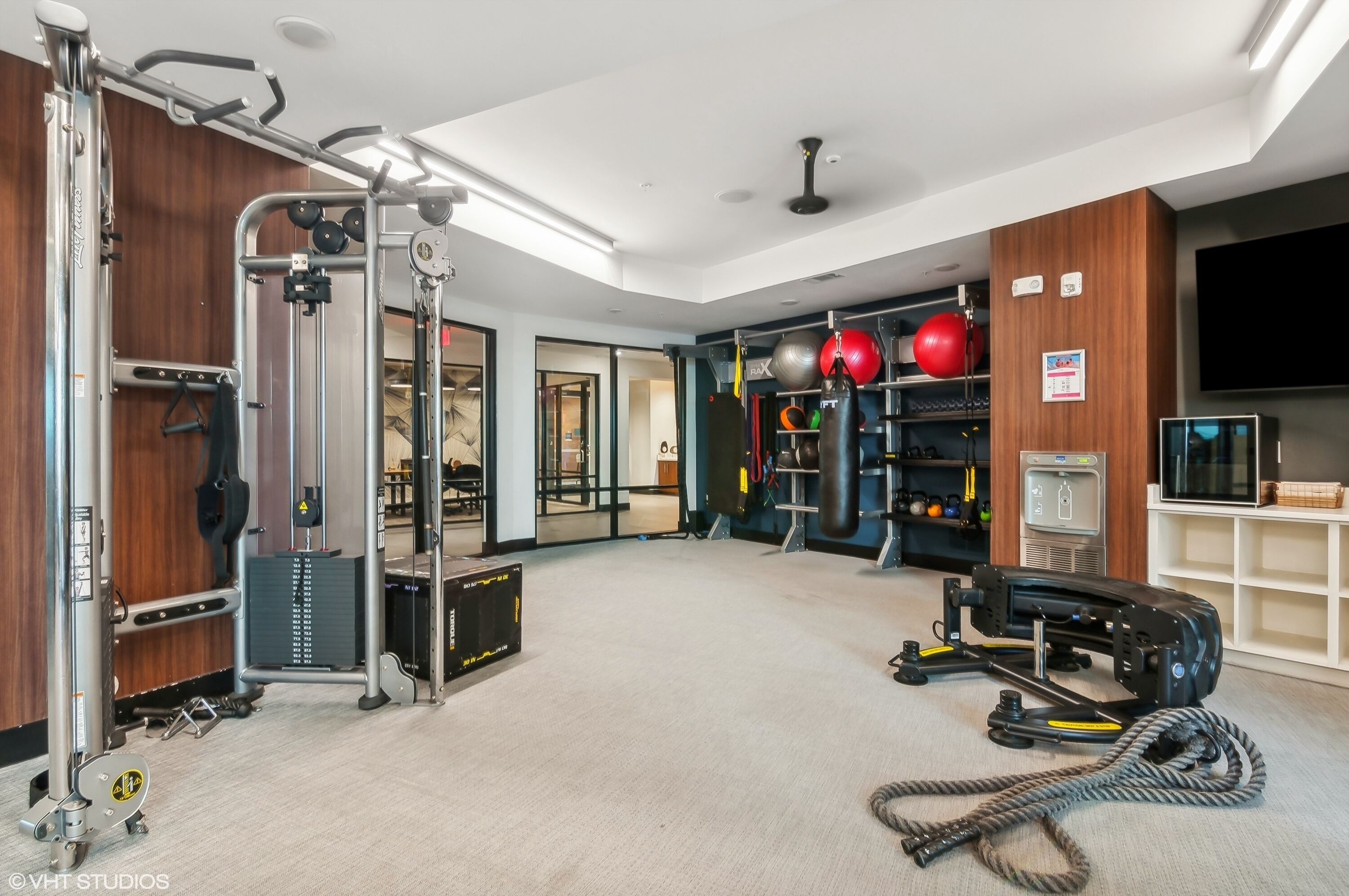 A gym with various exercise equipment, a ceiling fan, and a television on the wall.