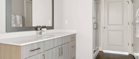 Une salle de bain moderne avec un grand miroir, un meuble-lavabo blanc et des armoires en bois.