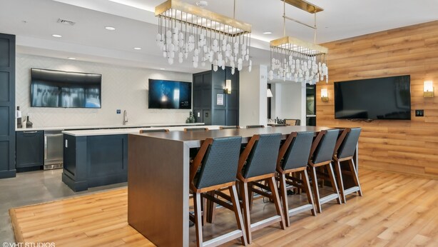 Una cocina moderna con una isla central, taburetes de bar e iluminación colgante.