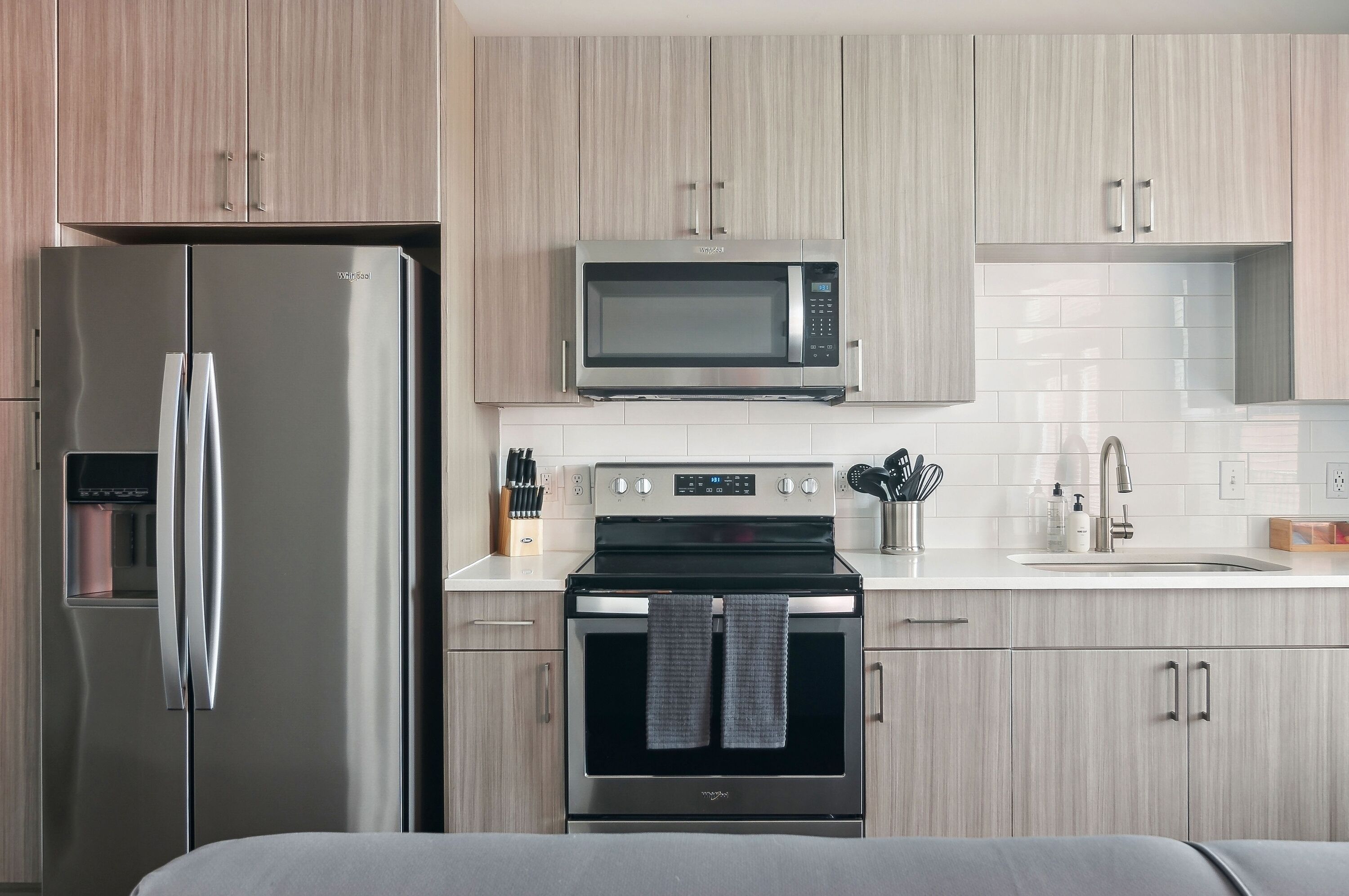A modern kitchen with stainless steel appliances, a microwave, oven, and a water dispenser.