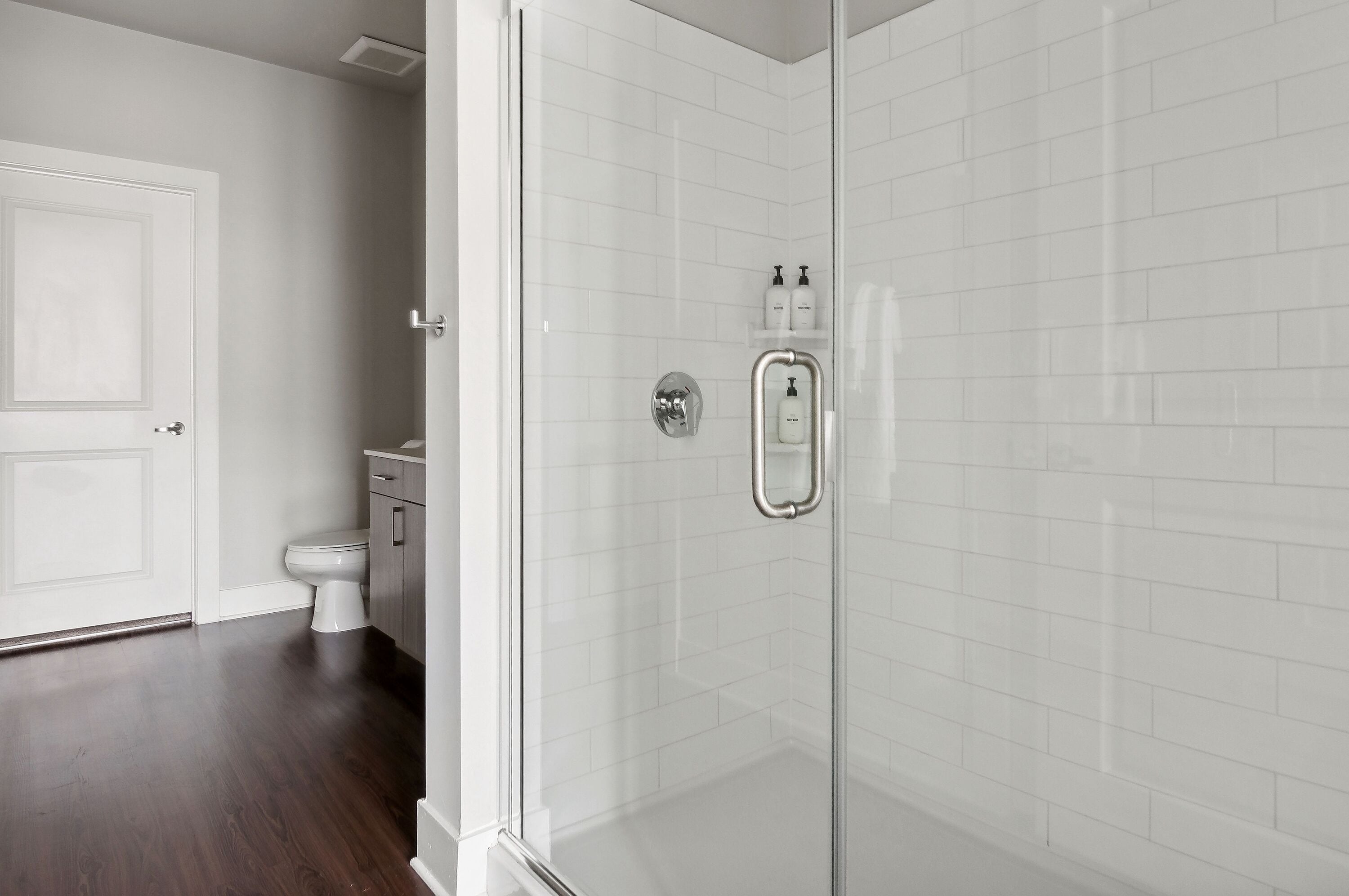 Een moderne badkamer met een douchecabine van glas, een wit toilet en een wastafel met spiegel.