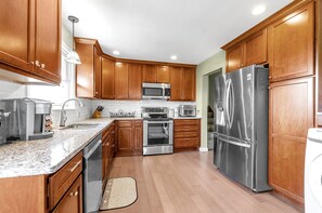 A modern kitchen with wooden cabinets, stainless steel appliances, and a granite countertop.