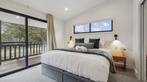 A bedroom with a large bed, a view of the outdoors, and a window with a view of the sky. - Nowhere Cottage rural retreat (Crackenback)