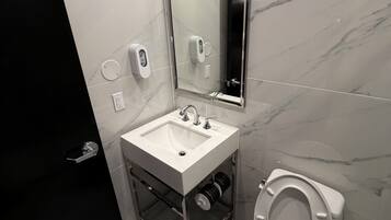 Un bany modern amb un lavabo blanc, un vàter i un mirall.
