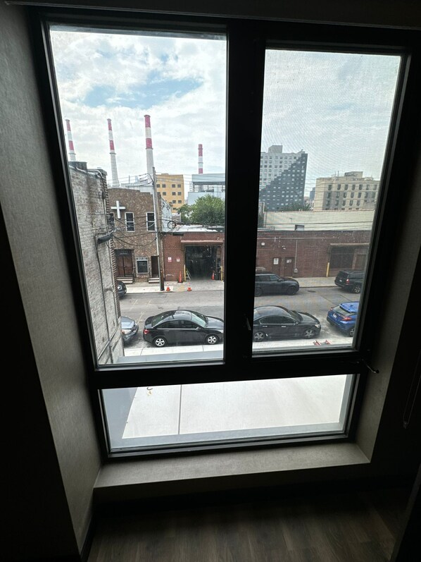 A view from a window of a building with a brick facade, a cross, and several cars parked outside. - LUX HOTEL (Long Island City)