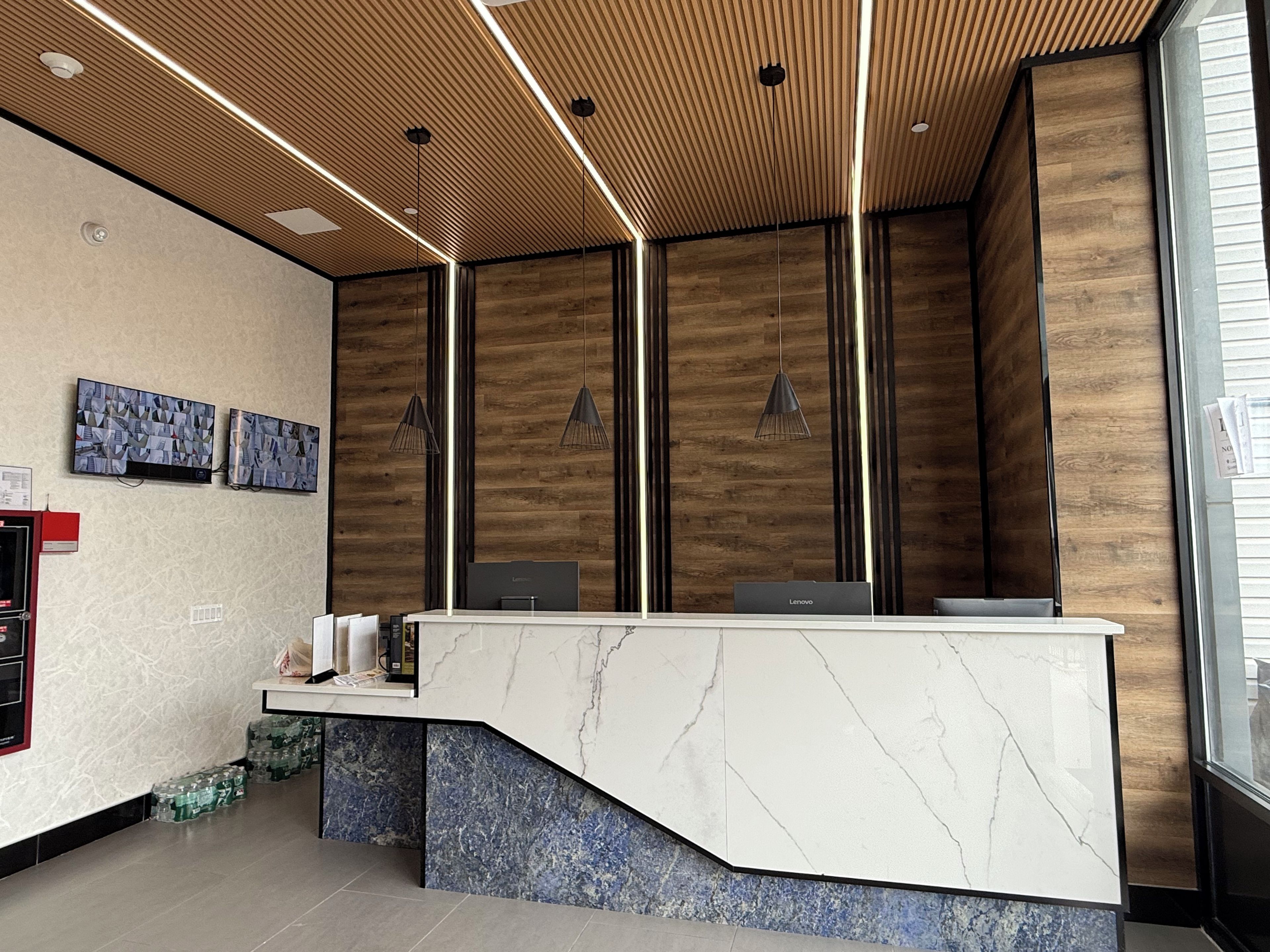 A reception desk with a marble top, wooden panel walls, and pendant lighting.