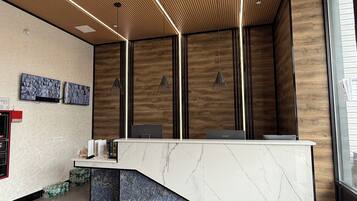 A reception desk with a marble top, wooden panel walls, and pendant lighting.