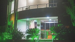 A two-story hotel with a sign reading "Bela Vista Hotel" and a phone number. There are steps leading to the entrance, and the building has a modern design with glass windows.