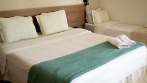 A hotel room with a large bed, a smaller bed, and a nightstand with a lamp.