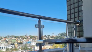 A balcony railing with a clear view of a cityscape in the background.
