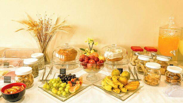 A buffet with various food items including fruits, bread, and condiments.