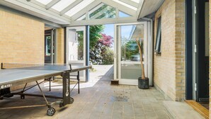 Un espacio exterior cubierto con una mesa de ping pong, una planta en maceta y un muro de ladrillo.