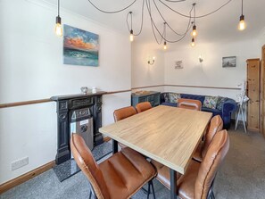 A dining area with a wooden table, leather chairs, a vintage jukebox, and a painting of a sunset. - Swinton Mill Farm Cottage (Swinton Mills)