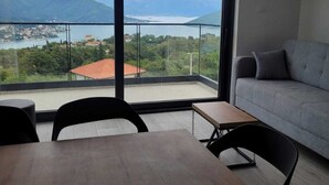 A modern living room with a large balcony, a grey sofa, and a wooden table.