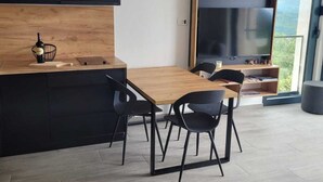 A modern kitchen with a wooden island, black cabinets, and a large TV.