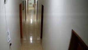 Un long couloir étroit, doté d’un sol carrelé et de murs blancs.