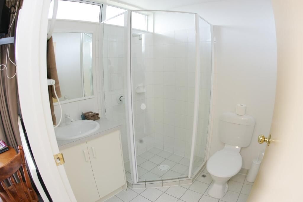 A bathroom with a glass-enclosed shower, a toilet, and a sink.