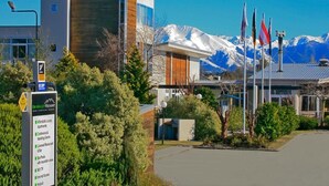A modern building with a sign listing amenities like affordable luxury apartments, a conference center, and a licensed restaurant. - Brinkley Resort (Methven)
