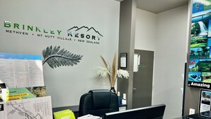 A reception desk at Brinkley Resort with a map, brochures, and a framed fern decoration. - Brinkley Resort (Methven)