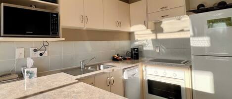 A modern kitchen with a microwave, stove, sink, and cabinets.