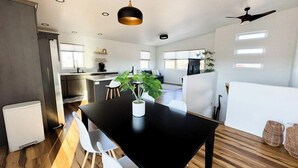 A modern kitchen with a black dining table, white chairs, and a potted plant.