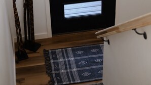 A black door with two windows, a wooden handrail, and a patterned rug on a wooden floor.