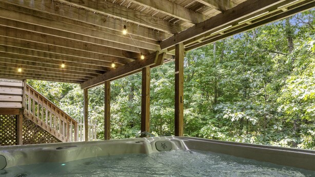 A hot tub area with wooden beams and a view of a forest. - Trendy Great Pond Escape! HotTub Open! Sleeps 9! (Falmouth)