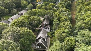 An aerial view of a residential area with multiple houses surrounded by dense trees and a body of water in the background. - Trendy Great Pond Escape! HotTub Open! Sleeps 9! (Falmouth)