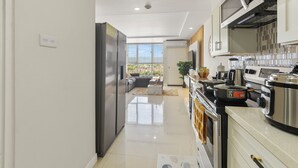 Une cuisine moderne dotée d’appareils électroménagers en acier inoxydable, d’une grande fenêtre et offrant une vue sur l’extérieur.