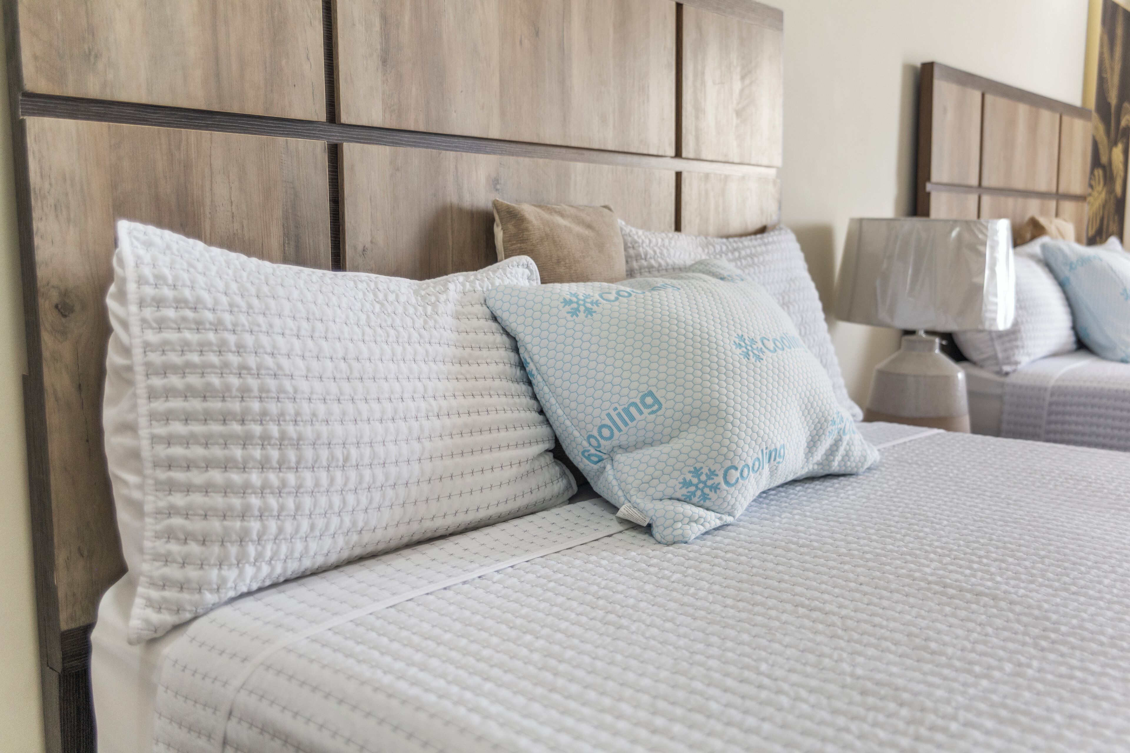 A neatly made bed with a headboard, pillows, and a bedside table with a lamp.