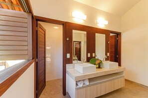 A modern bathroom with a large mirror, two sinks, and a vanity with a towel rack. - Pousada Vila Gostoso (São Miguel do Gostoso)
