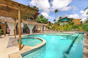 A pool area with a wooden deck, lounge chairs, and a covered seating area. - Pousada Vila Gostoso (São Miguel do Gostoso)